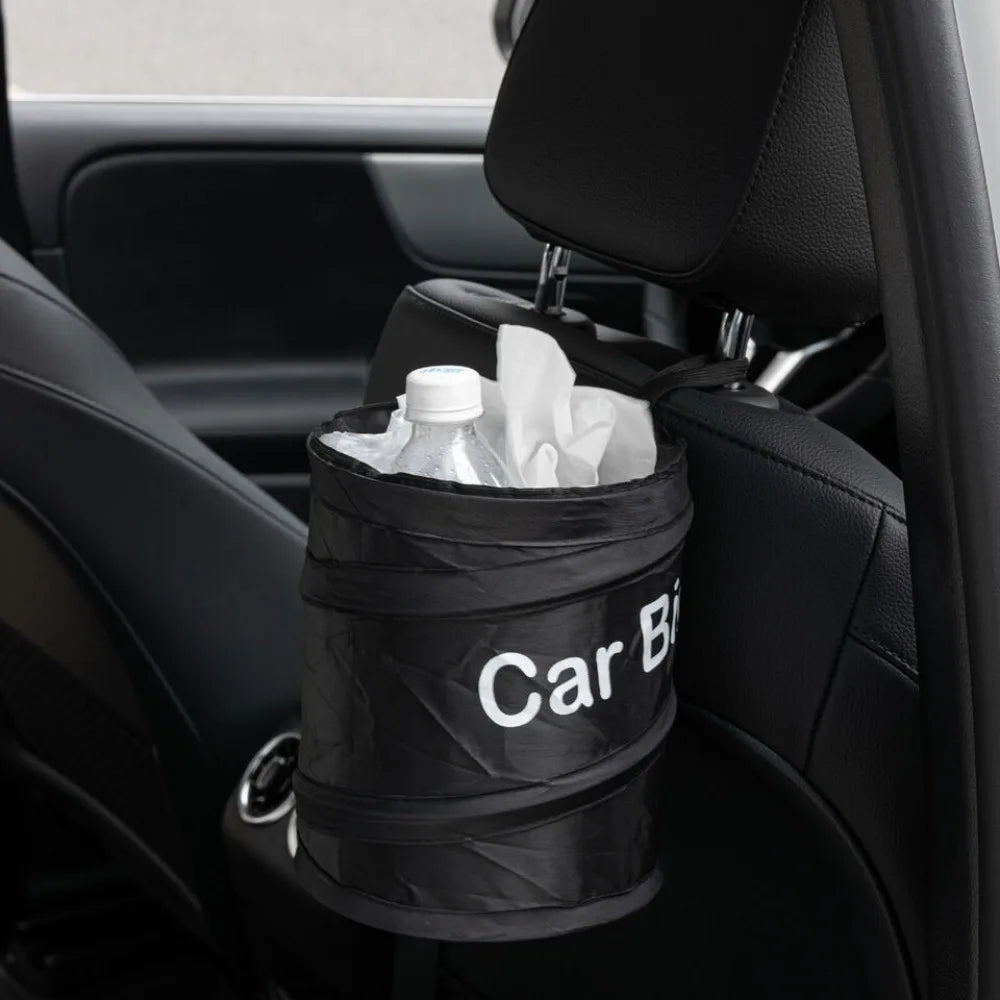 A black waterproof collapsible car trash can bag filled with white paper, placed in a car interior.