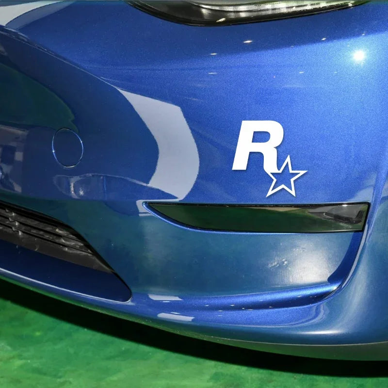 Close-up of a blue car body featuring a white reflective R star decal on the hood.