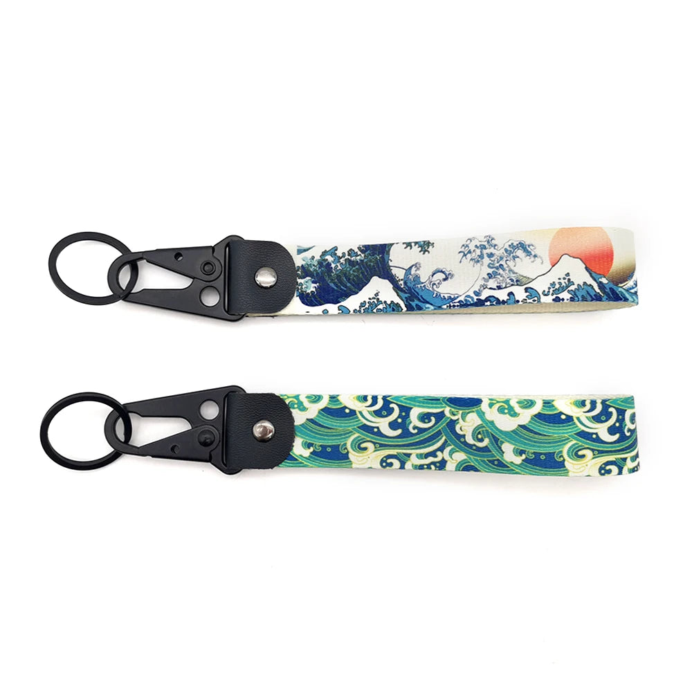 A pair of black JDM car keychain lanyards featuring a blue and white wave pattern.
