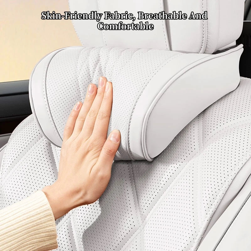 A hand rests on a white, breathable fabric ergonomic lumbar and neck pillow designed for car seat comfort.