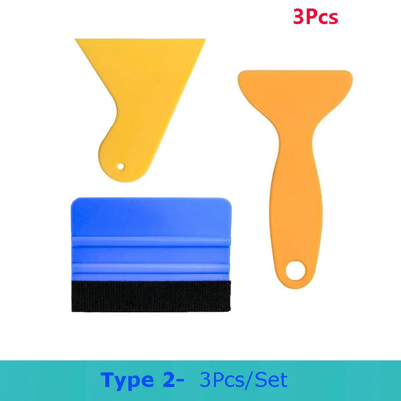 A set of three vinyl wrapping tools including a yellow spatula, an orange spatula, and a blue tool.