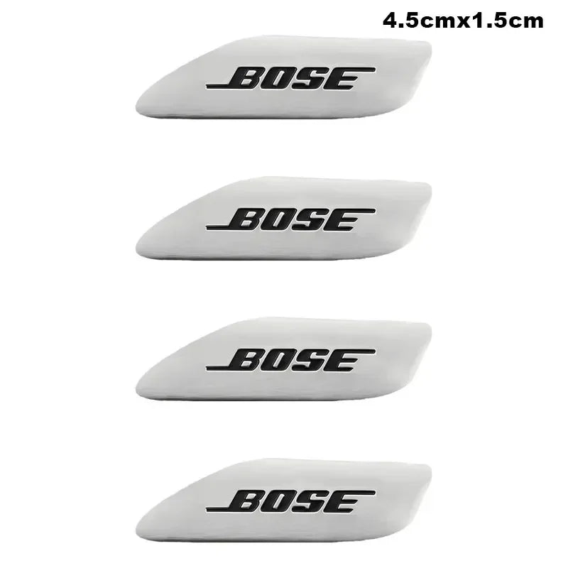 Four white Bose car audio emblems shown from different angles.