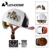A white motorcycle helmet with gold Boss logo and tinted visor, shown alongside accessories like a leather helmet and goggles