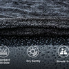 Close-up of a dark gray microfiber cloth being used to wipe a wet surface, highlighting its absorbent and streak-free propert