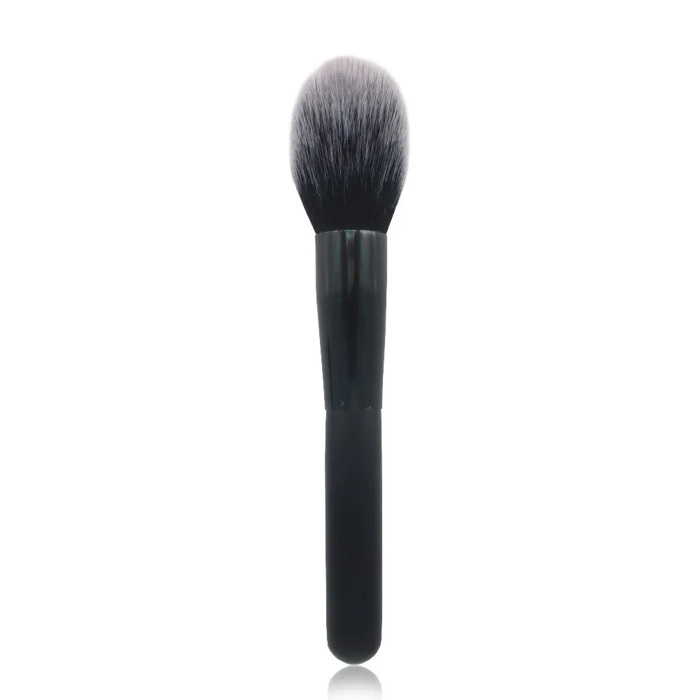 Un pinceau de maquillage noir à poils synthétiques denses et souples, sur fond blanc.
