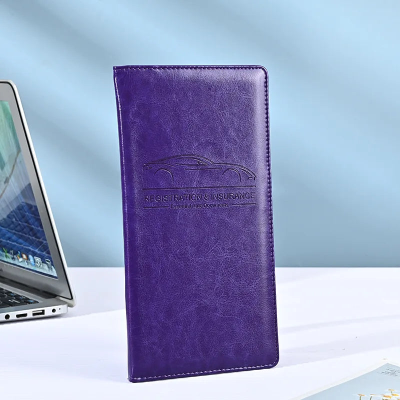 A purple premium PU leather vehicle organizer wallet with embossed text on a white surface.