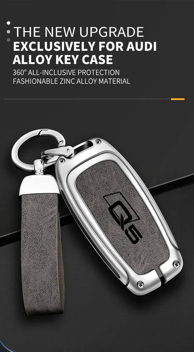 A close-up of a silver zinc alloy key case for an Audi Q5, featuring a textured dark gray cover and a leather strap.
