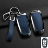 A black aluminum alloy key fob cover with a blue leather strap and keyring shown against a dark background.