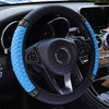 A close-up view of a black steering wheel with a bright blue quilted leather cover and silver accents.