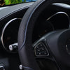 Close-up view of a black embossed leather steering wheel with blue stitching and controls.