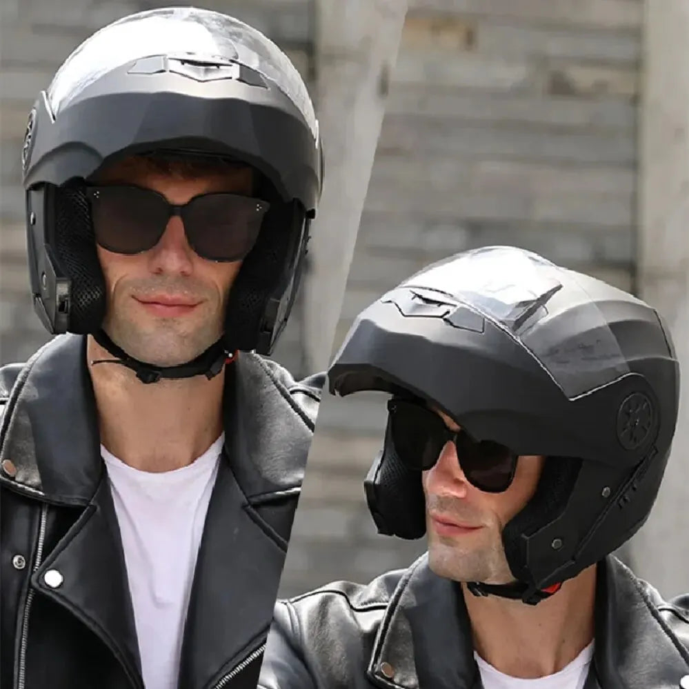 A man wearing a black motorcycle helmet and sunglasses stands in an outdoor setting.