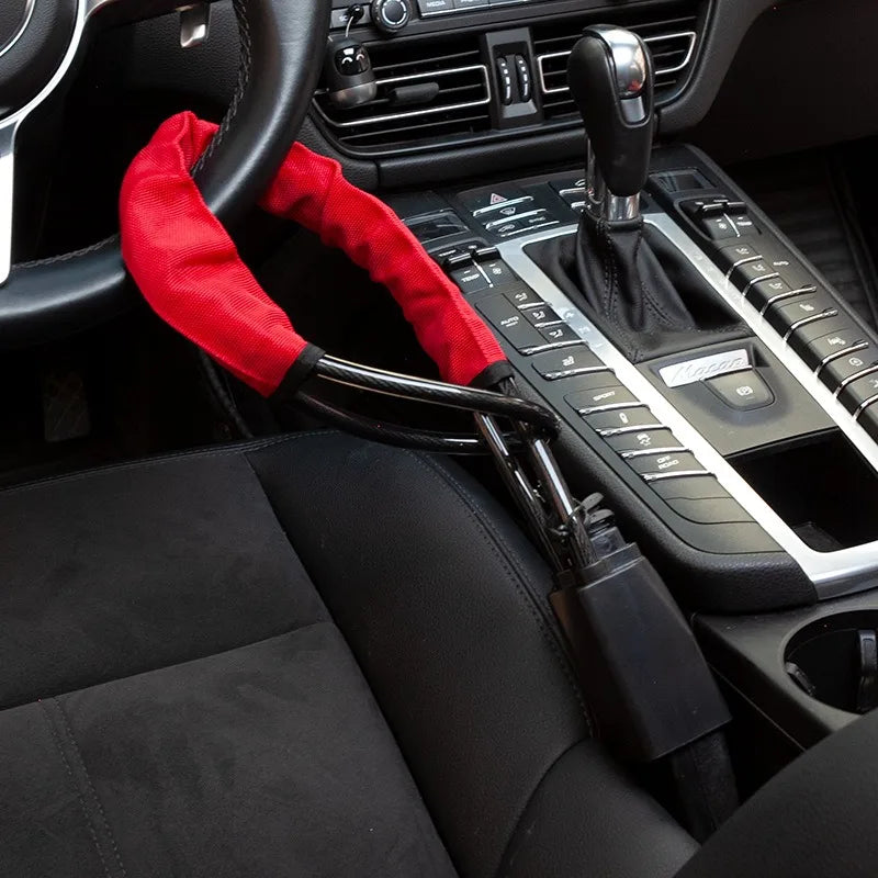 Interior view of a car showing a steering wheel, red seatbelt, and control panel.