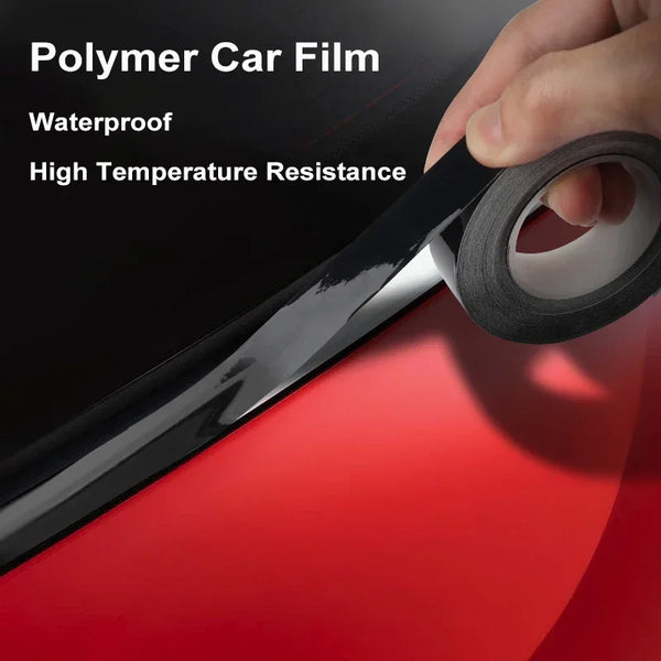 A hand is applying a roll of clear polymer car film onto a glossy black window trim.