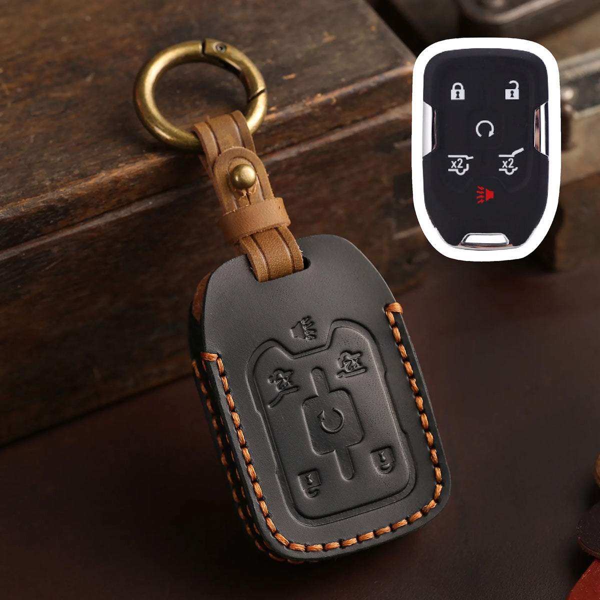 A dark brown leather key cover with a brass ring attached, featuring cutouts for Chevrolet and GMC truck keys.