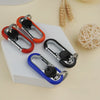 A collection of red and black carabiner lock keychains displayed on a white surface next to wheat stalks.