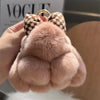 A light pink plush bunny keychain with soft fur and a gold ring is being held in a hand.