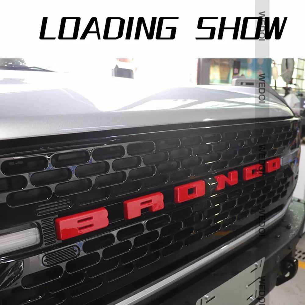 Gros plan de la calandre noire d'un Ford Bronco avec un cache de lettres rouges.