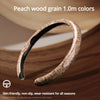 A close-up of a leather steering wheel cover with a peach wood grain texture shown on a wooden surface.
