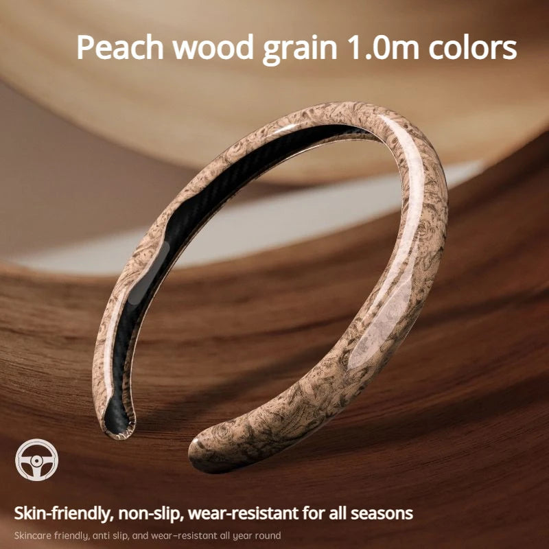 A close-up of a leather steering wheel cover with a peach wood grain texture shown on a wooden surface.