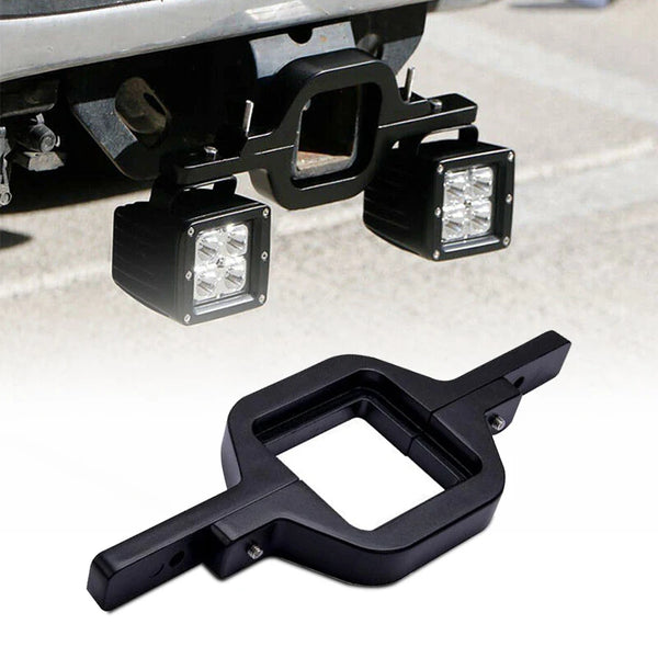Black dual LED pod mount brackets for a 2.5-inch tow hitch visible on a vehicle frame.