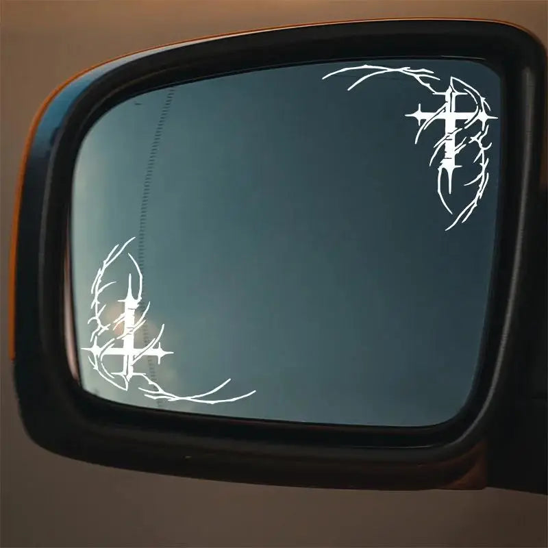 A close-up view of a car window featuring white gothic thorn cross decals.