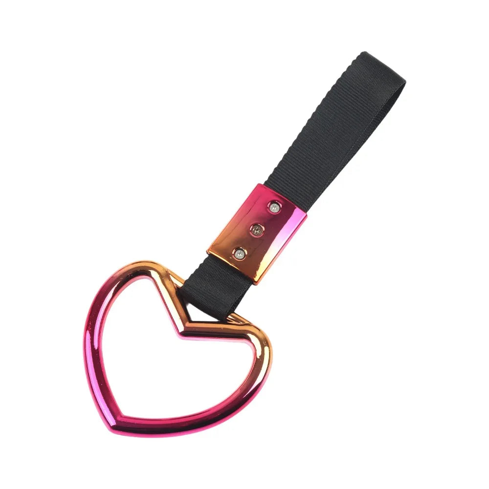 A holographic heart-shaped car handle accessory with a black strap and gold accents.