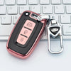 A pink metallic car key case cover with a silver clasp is placed on a white keyboard.
