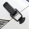 Black carbon fiber pull buckle repair clips attached to a white car surface.