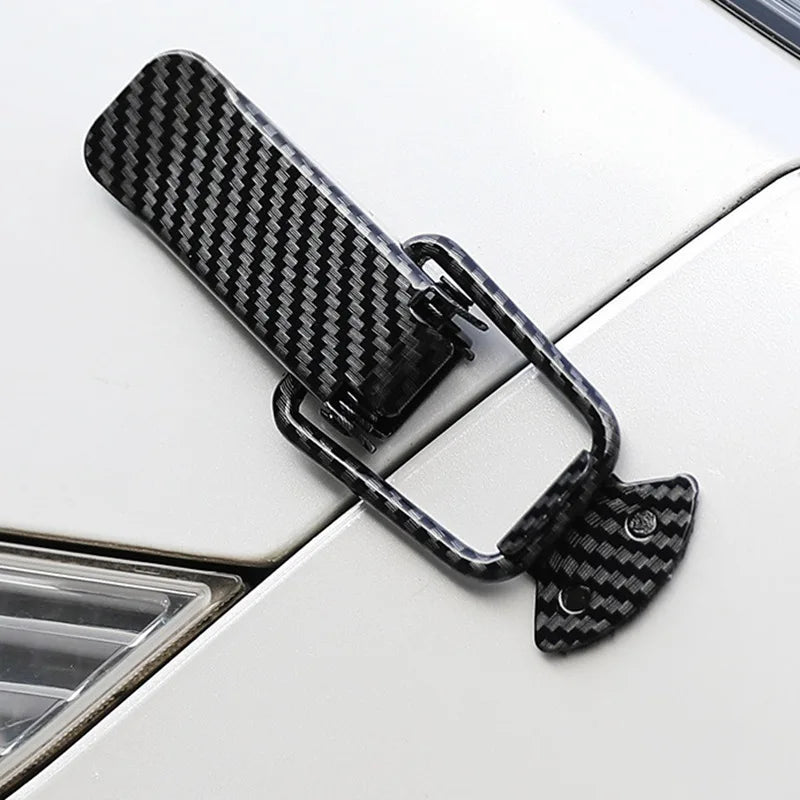 Black carbon fiber pull buckle repair clips attached to a white car surface.
