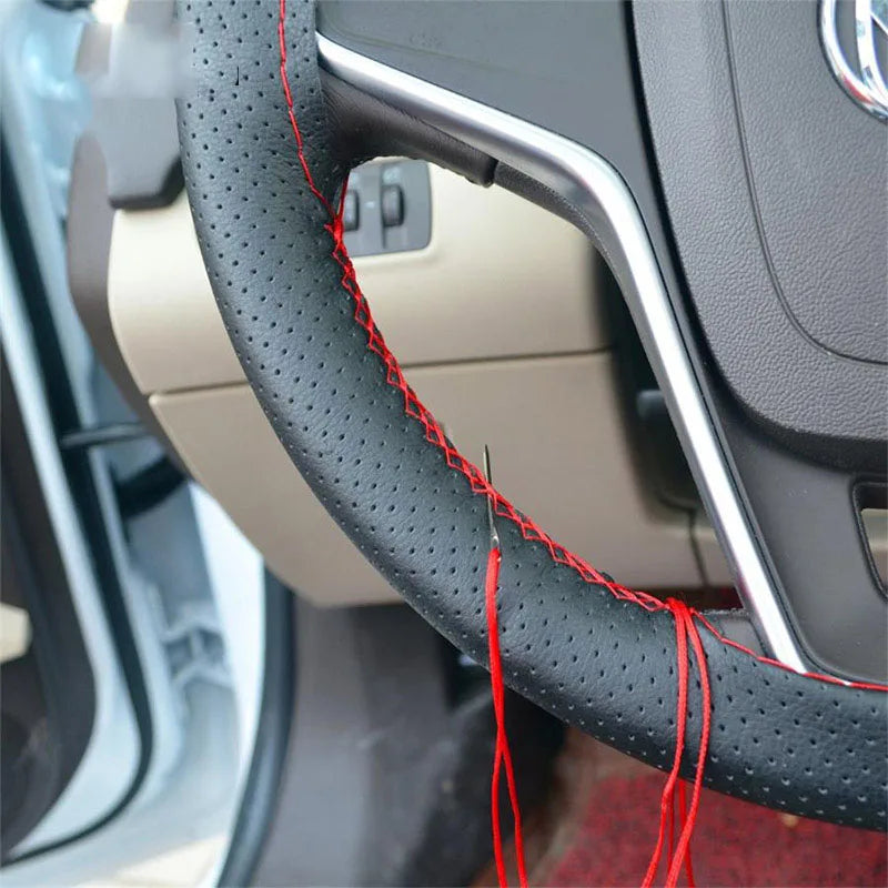 A close-up view of a black steering wheel cover being sewn with red thread using a sewing kit.