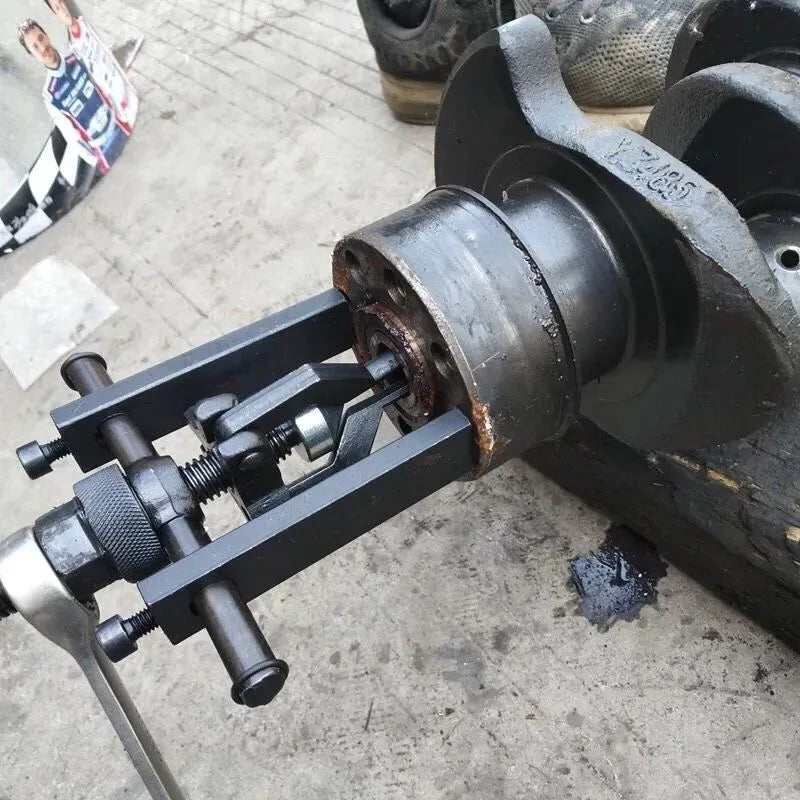 A close-up view of a black three-claw bearing puller tool used for internal and external removal.