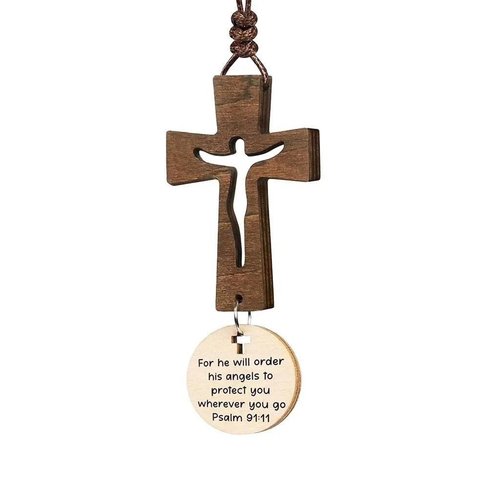 A wooden cross ornament with a hanging loop and an engraved message for protection.