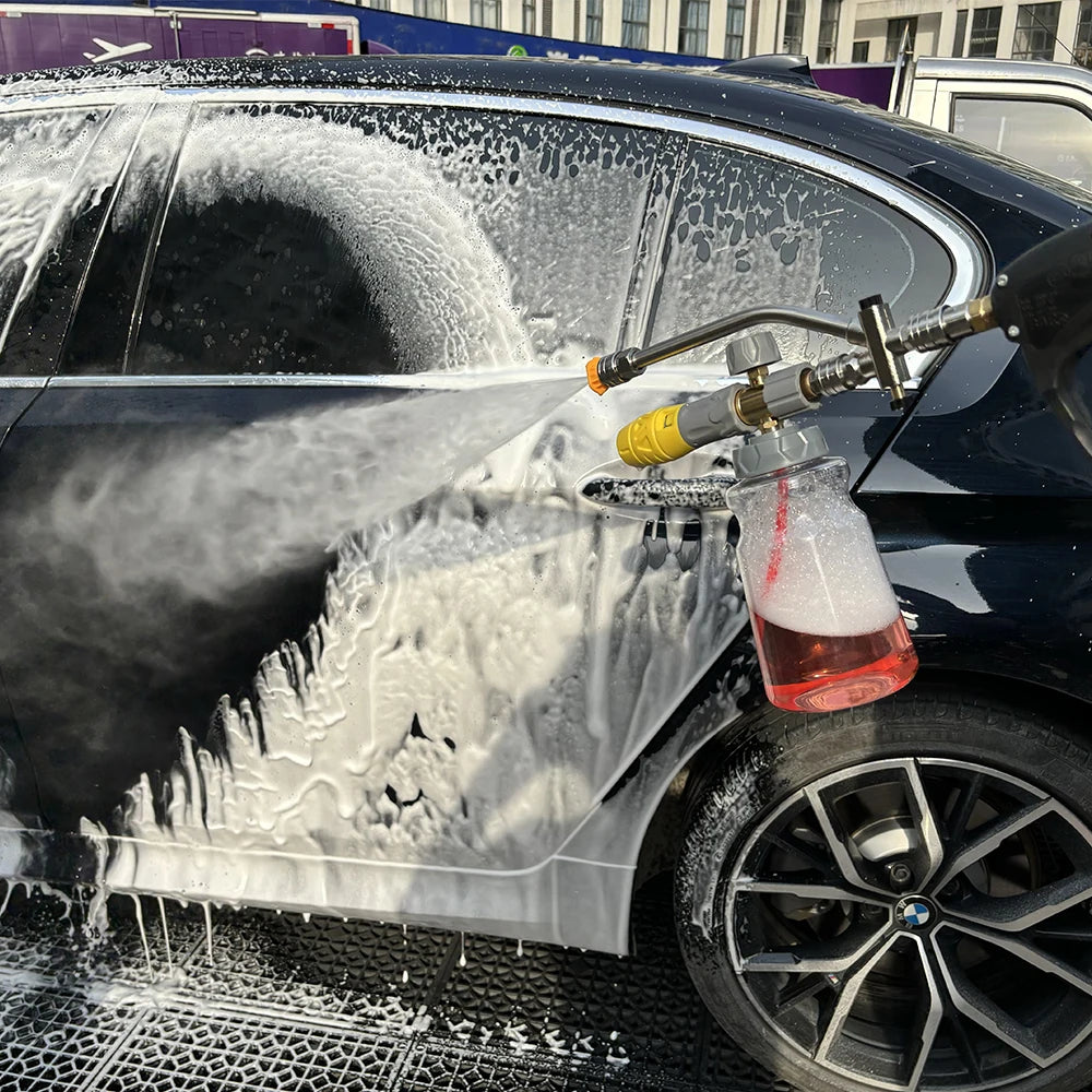 A pressure washer foam cannon adapter is spraying white foam onto the side of a dark car.