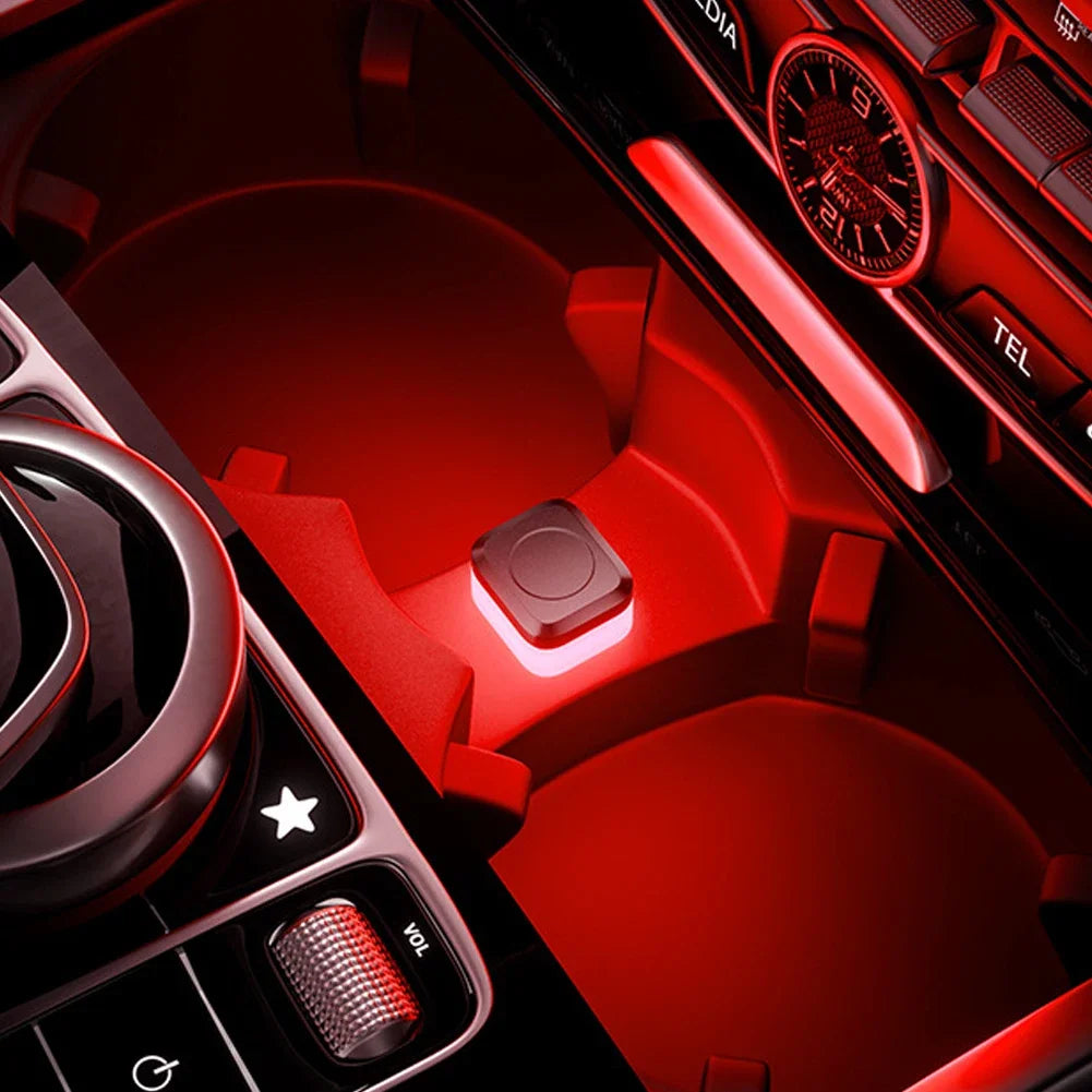 Close-up view of a red car interior featuring ambient LED lights and controls.