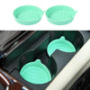 A set of two light green silicone cup holders or coasters shown in a black holder.