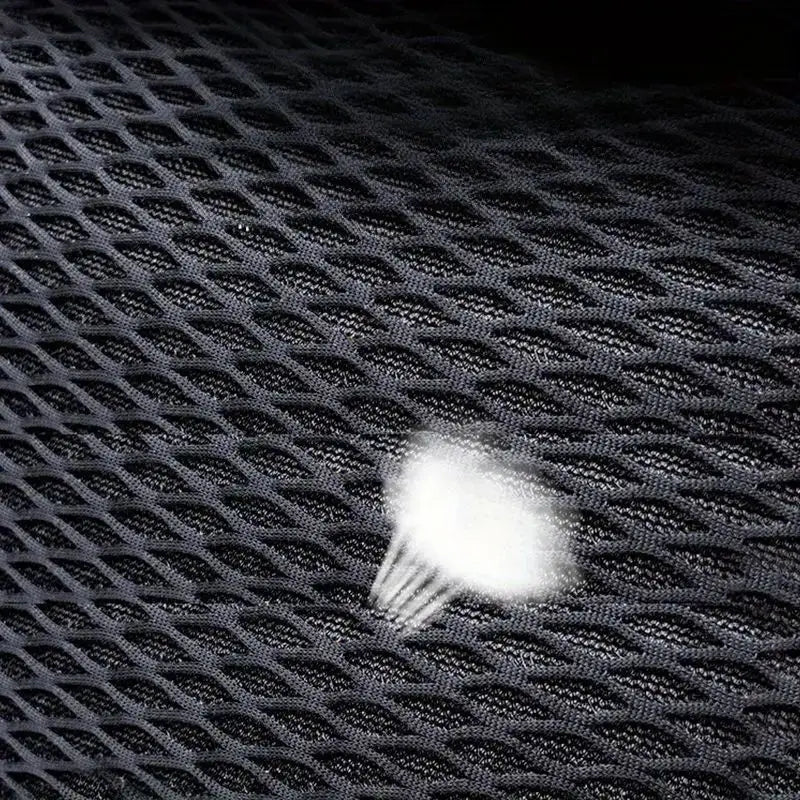 A close-up view of a white neck support cushion placed on a dark, textured mesh surface.