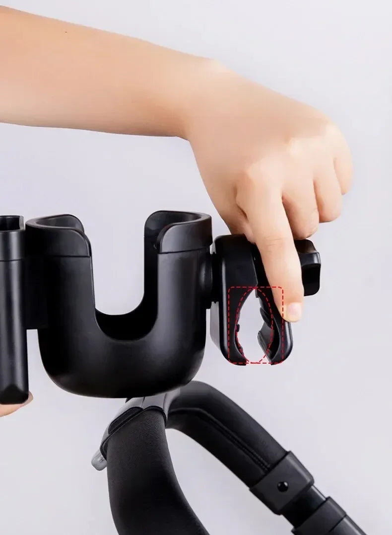 Une main tient un support téléphone et tasse multifonctionnel noir pour poussette.
