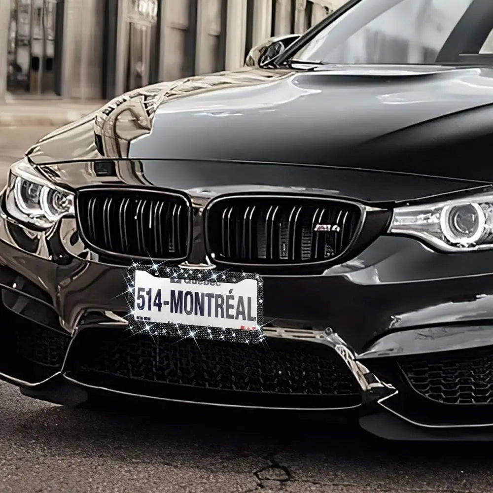 A close-up of a black BMW front grille and headlights with a sparkly diamond rhinestone license plate frame.