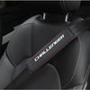 Close-up of a black car seat belt shoulder strap pad with red stitching on a dark gray seat interior.