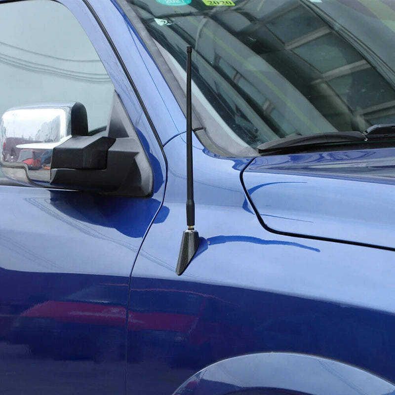 Close-up of a black carbon fiber look antenna base trim mounted on the side of a blue Dodge RAM truck.