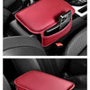 A red leather car armrest storage organizer pad is shown placed in the interior of a car.
