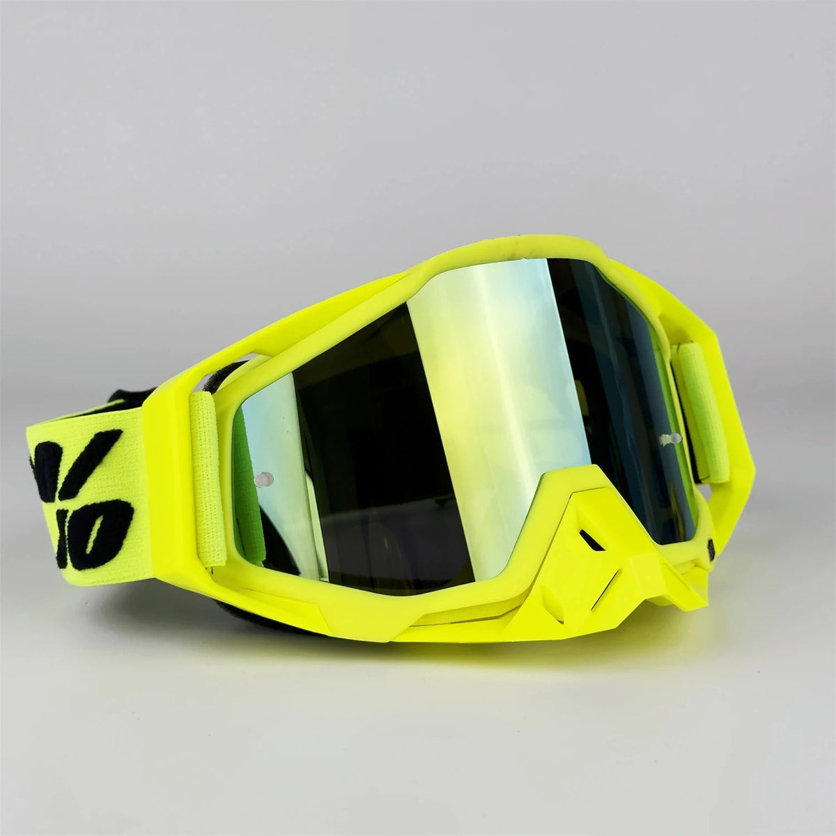 A bright yellow pair of all-weather off-road motorcycle riding goggles resting on a light gray surface.