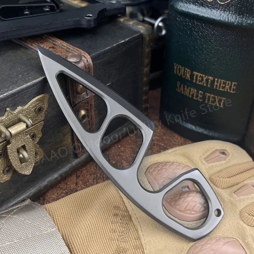 A silver fixed blade survival knife is shown resting on a tan glove and dark surface.