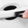 A hand is applying a black protection sticker to a white car door handle.