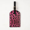 A black leather passport holder with a pink leopard print design and a gold-toned metal clasp.