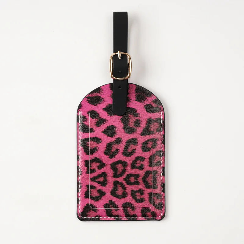 A black leather passport holder with a pink leopard print design and a gold-toned metal clasp.