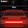 A close-up view of a red LED light strip installed on the rear bumper of a car, demonstrating a reflective safety sticker.