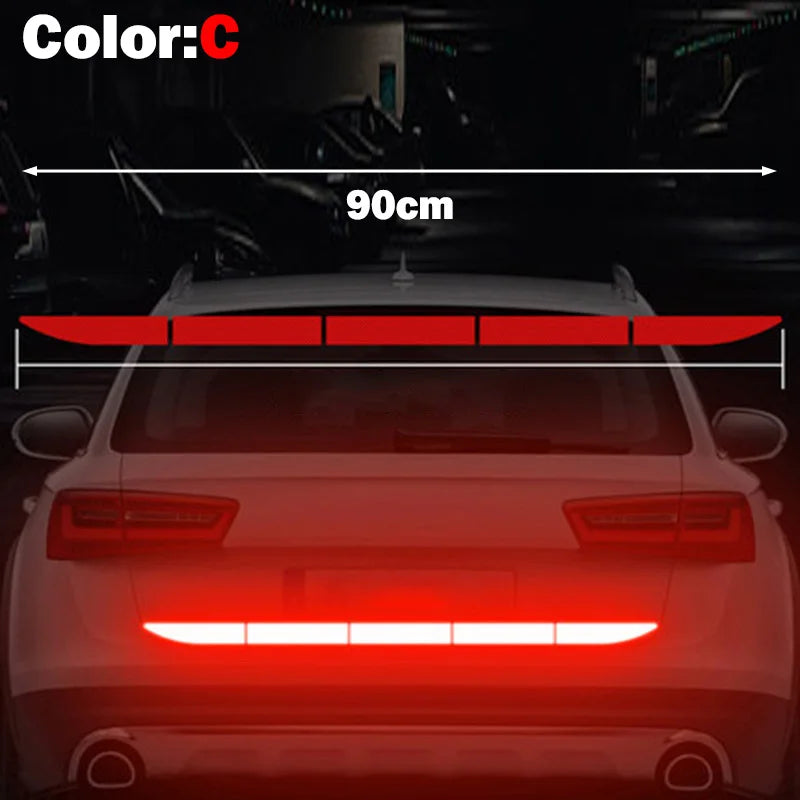 A close-up view of a red LED light strip installed on the rear bumper of a car, demonstrating a reflective safety sticker.