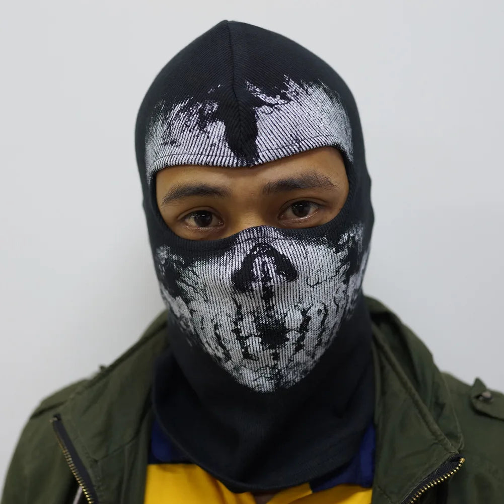 Una persona usando una máscara balaclava negra completa con patrón de calavera blanca, visible contra un fondo claro.
