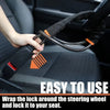 A hand is wrapping a black and orange anti-theft lock around a car steering wheel for security.